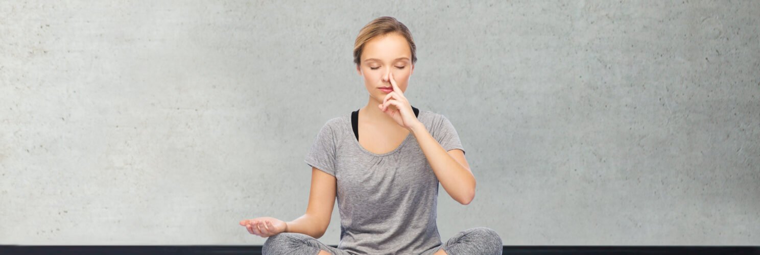 Kobieta siedząca po turecku na karimacie z palcem wskazującym lewej dłoni na nosie